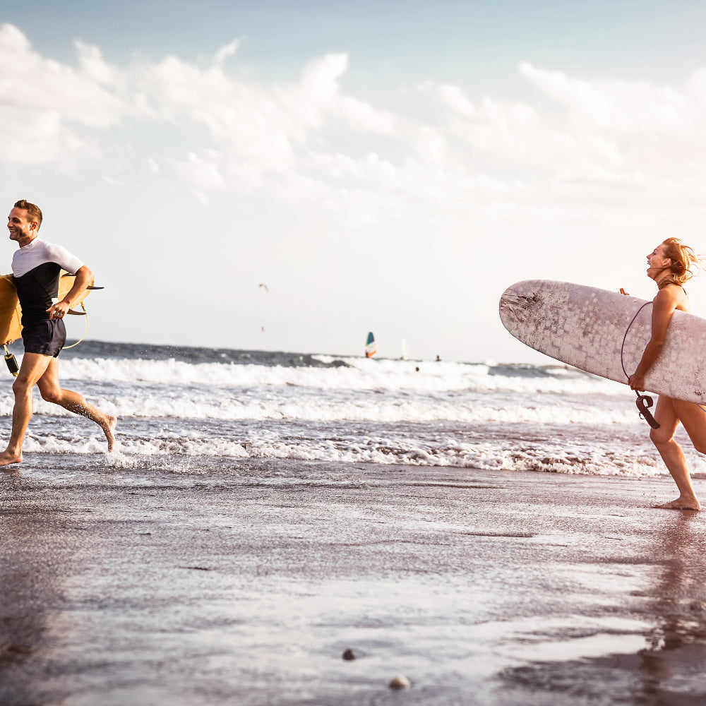 Two surfers running into the surf 