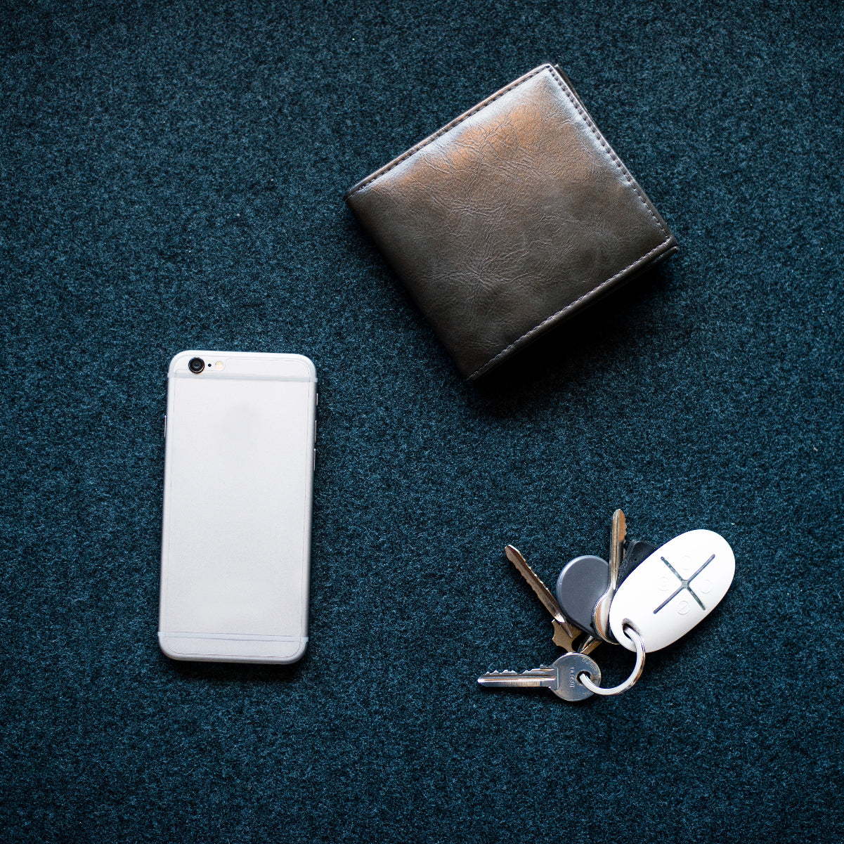 White AJAX SpaceControl on a keychain shown with keycard and wallet